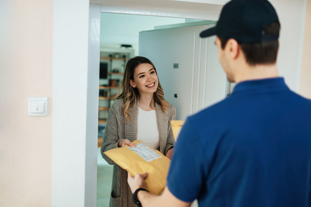 young happy woman receiving package from delivery man at home.